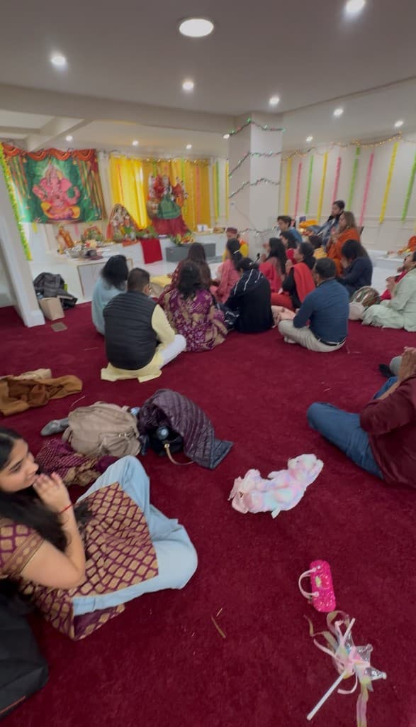 Devotees seated on the carpet during puja in front of the mandir darbar