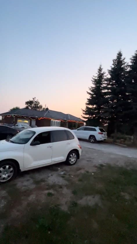 The property at dusk on 14 July 2025, with cars parked on the gravel driveway